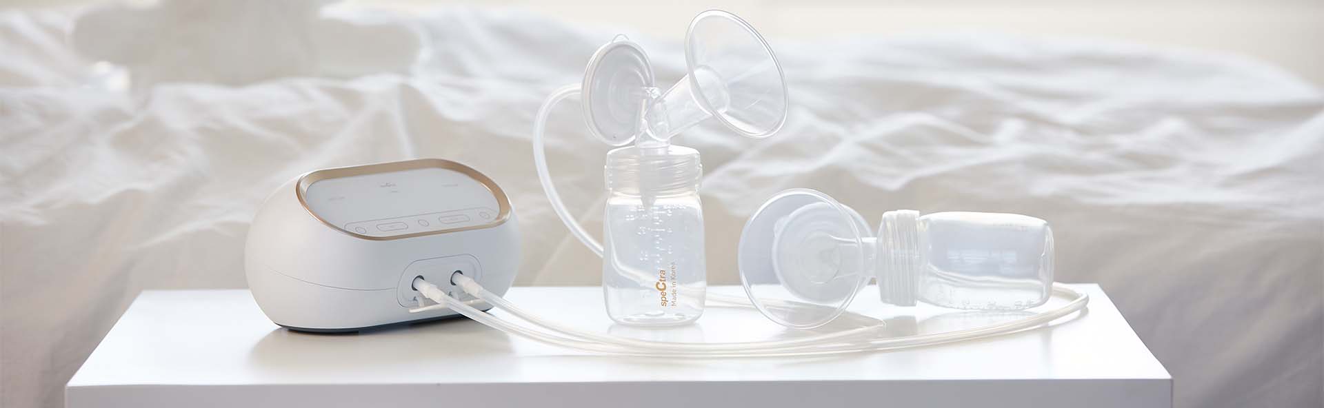 Spectra Korea dual compact breastpump with bottle on a table，Spectra 奶泵及其他配件